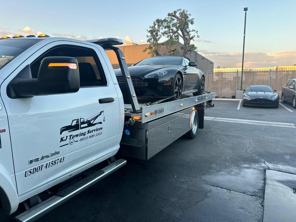 KJ Towing flatbed truck in Corona carrying a black sports car